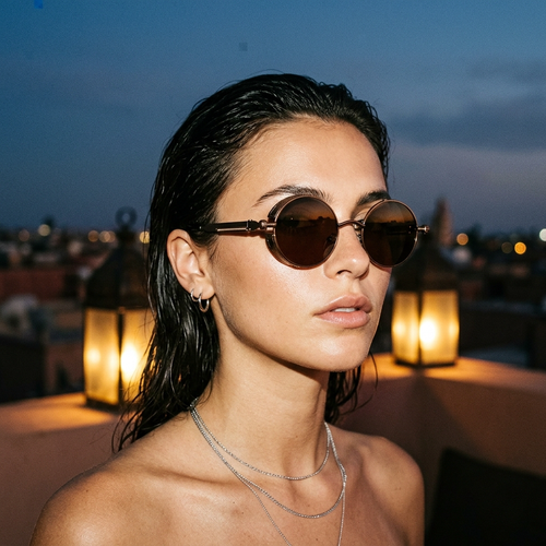 Woman wearing round steampunk sunglasses on a Marrakech villa rooftop at dusk