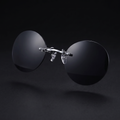 Round rimless clip-on sunglasses, black smoke mirror colorway, studio close-up — no temple arms