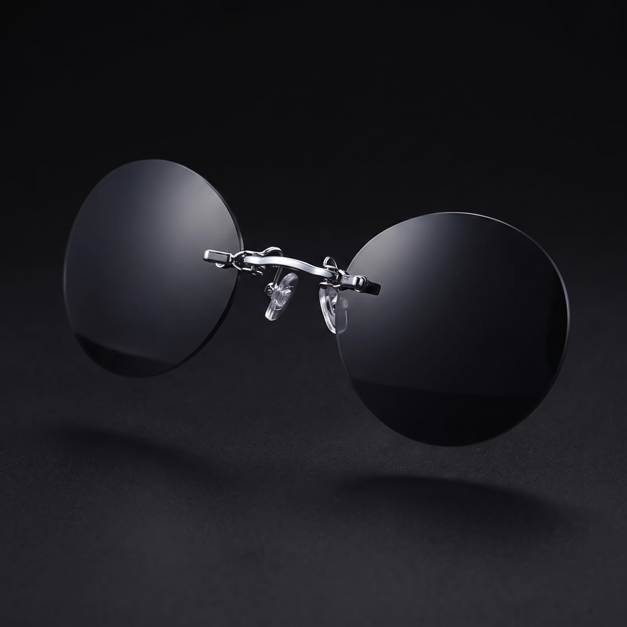 Round rimless clip-on sunglasses, black smoke mirror colorway, studio close-up — no temple arms