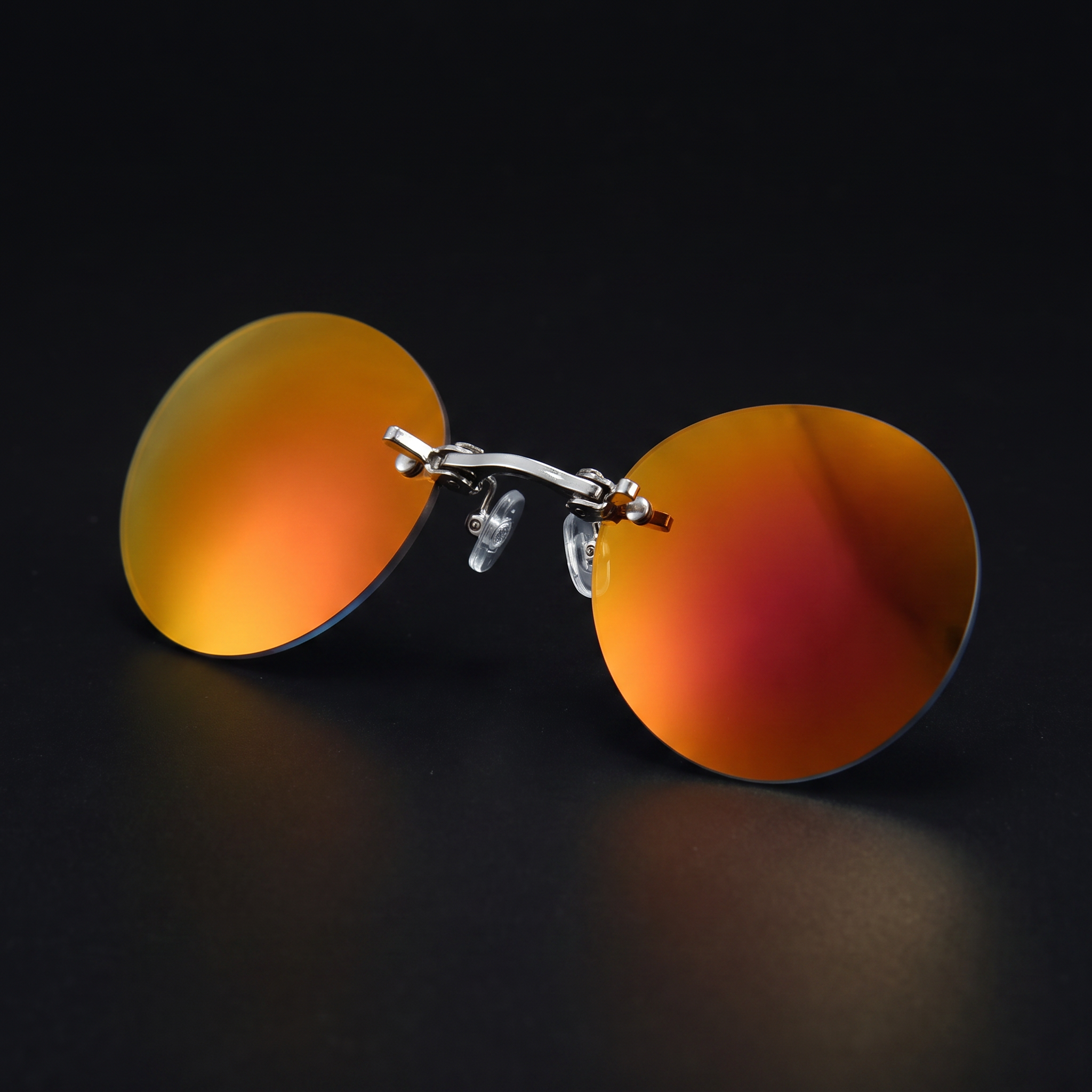 Round rimless clip-on sunglasses, sunset mirror colorway, studio close-up — no temple arms